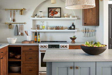 Photo of a medium sized country l-shaped kitchen/diner in Denver with a submerged sink, shaker cabinets, green cabinets, engineered stone countertops, beige splashback, metro tiled splashback, white appliances, light hardwood flooring, an island, brown floors, grey worktops and exposed beams.