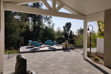 Inspiration for a large contemporary backyard concrete paver patio remodel in Orange County with a roof extension