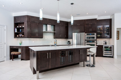 Kitchen - large transitional porcelain tile kitchen idea in Toronto with an undermount sink, shaker cabinets, dark wood cabinets, quartz countertops, white backsplash, glass tile backsplash, stainless steel appliances and an island