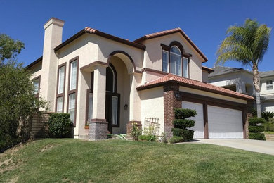 Photo of a mid-sized traditional two-storey stucco beige house exterior in Los Angeles with a hip roof and a tile roof.