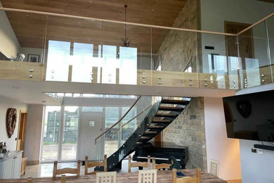 Staircase - mid-sized modern wooden curved open, glass railing and brick wall staircase idea in Hampshire