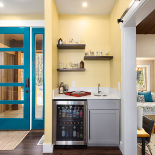 他の地域のラスティックスタイルのおしゃれなウェットバー (アンダーカウンターシンク、シェーカースタイル扉のキャビネット、グレーのキャビネット、黄色いキッチンパネル、濃色無垢フローリング、白いキッチンカウンター、クオーツストーンカウンター、茶色い床) の写真