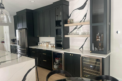 Inspiration for a huge transitional l-shaped light wood floor eat-in kitchen remodel in New York with a farmhouse sink, shaker cabinets, green cabinets, quartz countertops, white backsplash, quartz backsplash, stainless steel appliances, an island and white countertops