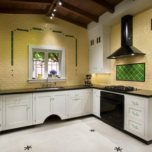 Réalisation d'une cuisine victorienne en U fermée et de taille moyenne avec un évier 2 bacs, un placard à porte affleurante, des portes de placard blanches, un plan de travail en granite, une crédence jaune, une crédence en carreau de céramique, un électroménager noir, un sol en carrelage de céramique et aucun îlot.