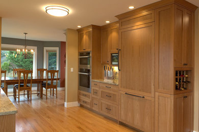 Example of a large transitional galley medium tone wood floor kitchen design in Seattle with an undermount sink, shaker cabinets, light wood cabinets, quartz countertops, ceramic backsplash, stainless steel appliances and an island