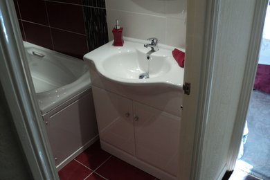 This is an example of a contemporary bathroom in Other with furniture-like cabinets, white cabinets, a two-piece toilet, red tile, ceramic tile, white walls and ceramic floors.