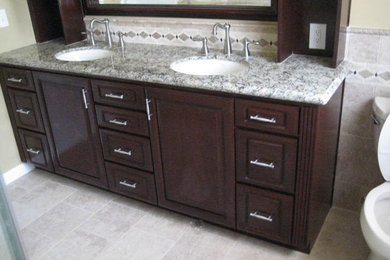 Bathroom - mid-sized traditional beige tile and ceramic tile ceramic tile and beige floor bathroom idea in Los Angeles with raised-panel cabinets, dark wood cabinets, a two-piece toilet, beige walls, an undermount sink and granite countertops