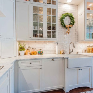 Bild på ett vintage kök, med en rustik diskho, luckor med glaspanel, beige skåp, marmorbänkskiva, beige stänkskydd och stänkskydd i tunnelbanekakel