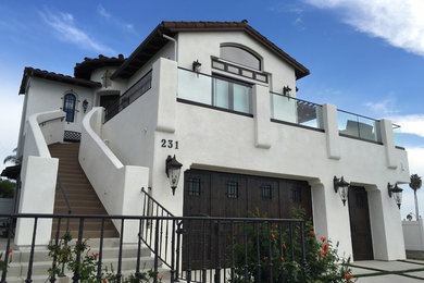 Large mediterranean white two-story stucco exterior home idea in Orange County with a shingle roof