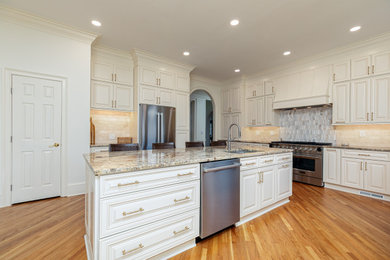 Kitchen - large modern light wood floor kitchen idea in Atlanta with an undermount sink, beaded inset cabinets, white cabinets, quartz countertops, ceramic backsplash, stainless steel appliances, an island, multicolored backsplash and multicolored countertops