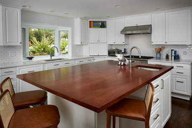Enclosed kitchen - large traditional u-shaped dark wood floor and brown floor enclosed kitchen idea in Seattle with an undermount sink, raised-panel cabinets, white cabinets, wood countertops, white backsplash, subway tile backsplash, stainless steel appliances and an island