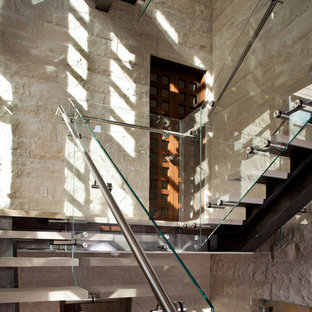 Photo of a medium sized contemporary u-shaped glass railing staircase in San Francisco with open risers and limestone treads.