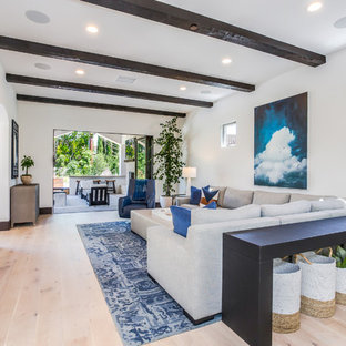 Photo of a mediterranean enclosed living room in Orange County with white walls, a ribbon fireplace, a metal fireplace surround, a wall mounted tv, light hardwood flooring and beige floors.