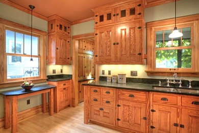 Mountain style l-shaped enclosed kitchen photo in Other with no island, raised-panel cabinets, light wood cabinets, soapstone countertops and stone tile backsplash