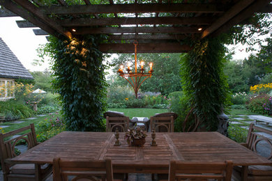 Example of a large classic backyard stone patio vertical garden design in Chicago with a pergola