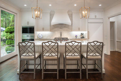 Photo of a mid-sized traditional u-shaped kitchen in Indianapolis with an undermount sink, raised-panel cabinets, white cabinets, quartz benchtops, white splashback, ceramic splashback, panelled appliances, medium hardwood floors, with island, brown floor and white benchtop.