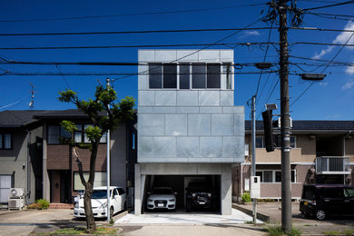 Ejemplo de fachada de casa gris y gris moderna de tamaño medio de tres plantas con revestimiento de metal, tejado plano y tejado de varios materiales