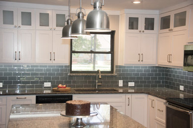 Inspiration for a mid-sized timeless l-shaped medium tone wood floor and brown floor eat-in kitchen remodel in Other with a double-bowl sink, shaker cabinets, white cabinets, granite countertops, gray backsplash, subway tile backsplash, black appliances and an island