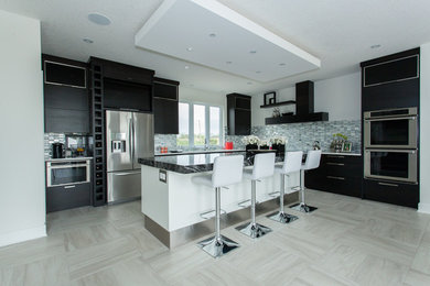 Inspiration for a large transitional u-shaped porcelain tile and gray floor eat-in kitchen remodel in Toronto with an undermount sink, flat-panel cabinets, black cabinets, quartz countertops, white backsplash, metal backsplash, stainless steel appliances, an island and white countertops