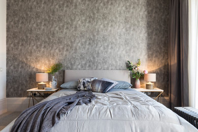 Inspiration for a large traditional master bedroom in Buckinghamshire with brown walls, carpet, no fireplace, beige floors, wallpapered walls and a feature wall.