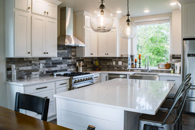 Mid-sized trendy l-shaped laminate floor and gray floor eat-in kitchen photo in Other with a farmhouse sink, shaker cabinets, white cabinets, quartz countertops, multicolored backsplash, ceramic backsplash, stainless steel appliances, an island and white countertops