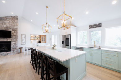 Large transitional l-shaped vinyl floor, beige floor and vaulted ceiling open concept kitchen photo in Vancouver with an undermount sink, shaker cabinets, turquoise cabinets, quartz countertops, white backsplash, ceramic backsplash, stainless steel appliances, an island and white countertops