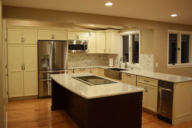 Transitional l-shaped light wood floor kitchen photo in Boston with a farmhouse sink, recessed-panel cabinets, white cabinets, granite countertops, porcelain backsplash, stainless steel appliances and an island