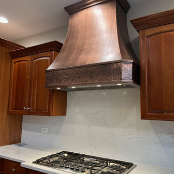 Handcrafted antique copper range hood featured in a classic traditional kitchen
