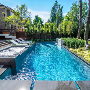 Modern inredning av en liten rektangulär pool på baksidan av huset, med en fontän och naturstensplattor