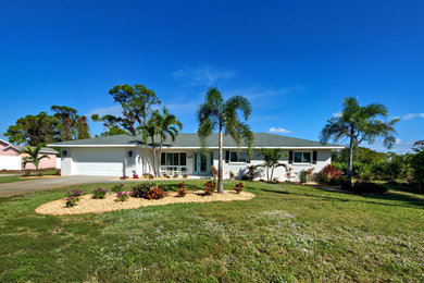 Example of a mid-sized beach style white one-story stucco exterior home design in Other with a shingle roof and a gray roof