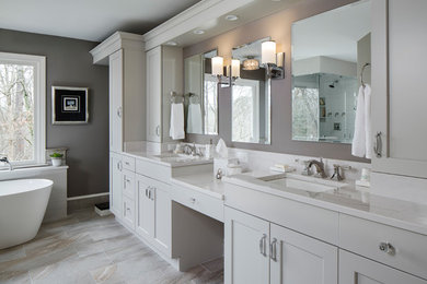 This is an example of a large transitional master bathroom in Atlanta with flat-panel cabinets, grey cabinets, a freestanding tub, a curbless shower, a two-piece toilet, gray tile, ceramic tile, grey walls, porcelain floors, an undermount sink, engineered quartz benchtops, grey floor and a hinged shower door.