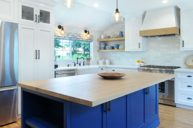 Inspiration for a mid-sized l-shaped eat-in kitchen in Los Angeles with a farmhouse sink, white cabinets, quartz benchtops, white splashback and with island.