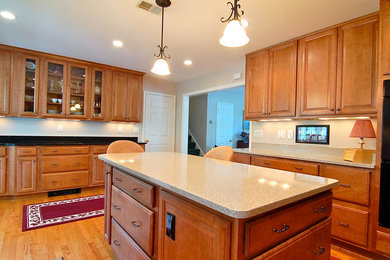 Kitchen - large traditional u-shaped light wood floor kitchen idea in DC Metro with an undermount sink, raised-panel cabinets, medium tone wood cabinets, quartz countertops, beige backsplash, black appliances and an island