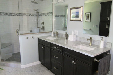 This is an example of a transitional master bathroom in New York with marble benchtops, stone tile, marble floors, recessed-panel cabinets, dark wood cabinets, an alcove shower, white tile, blue walls and an undermount sink.