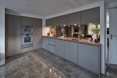 Photo of a medium sized contemporary l-shaped kitchen in Other with flat-panel cabinets, brown cabinets, quartz worktops, metallic splashback, mirror splashback, no island, brown floors and brown worktops.