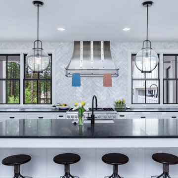Modern kitchen with a stainless steel range hood features a pot rack