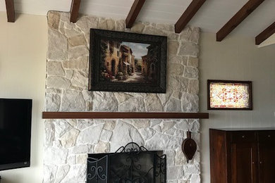 Photo of a large arts and crafts open concept family room in San Diego with beige walls, dark hardwood floors, a standard fireplace, a stone fireplace surround, a freestanding tv and brown floor.