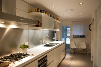 Design ideas for a mid-sized transitional single-wall separate kitchen in Barcelona with flat-panel cabinets, white cabinets, laminate benchtops, metallic splashback, metal splashback, no island, a double-bowl sink, panelled appliances, porcelain floors and grey floor.