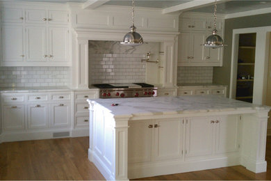 Mid-sized elegant l-shaped light wood floor open concept kitchen photo in Chicago with a farmhouse sink, recessed-panel cabinets, yellow cabinets, marble countertops, white backsplash, stone slab backsplash, paneled appliances and two islands