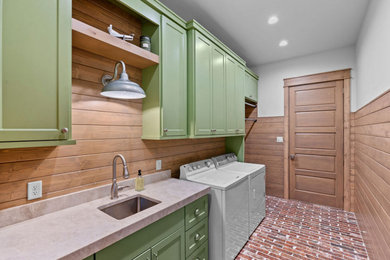Example of a mountain style single-wall brick floor and wood wall laundry room design in Dallas with an undermount sink, shaker cabinets, green cabinets, shiplap backsplash, a side-by-side washer/dryer and white countertops