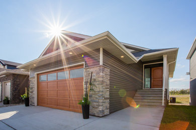 Photo of a mid-sized modern one-storey grey exterior in Calgary with vinyl siding and a gable roof.