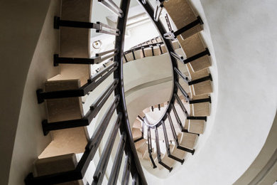 Foto de escalera curva bohemia de tamaño medio con escalones de mármol, contrahuellas de hormigón y barandilla de metal