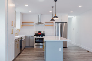 Inspiration for a mid-sized mid-century modern l-shaped plywood floor and gray floor enclosed kitchen remodel in Phoenix with a single-bowl sink, shaker cabinets, white cabinets, quartz countertops, white backsplash, ceramic backsplash, stainless steel appliances, an island and white countertops