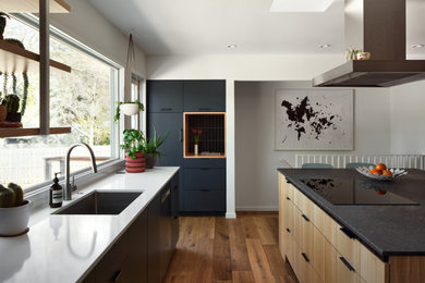 Mid-sized minimalist l-shaped medium tone wood floor and brown floor kitchen photo in Minneapolis with an undermount sink, flat-panel cabinets, gray cabinets, quartz countertops, black backsplash, ceramic backsplash, stainless steel appliances, an island and white countertops
