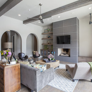 Imagen de salón para visitas mediterráneo con paredes grises, suelo de madera clara, chimenea tradicional, marco de chimenea de baldosas y/o azulejos y televisor colgado en la pared