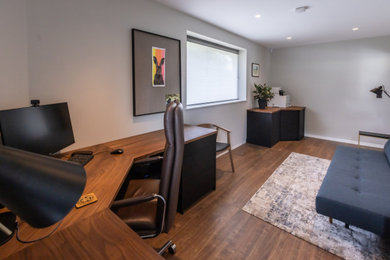 Photo of a medium sized modern home office in West Midlands with grey walls, laminate floors, a built-in desk and brown floors.