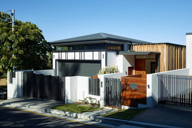 Photo of a large modern three-storey concrete white house exterior in Brisbane with a hip roof and a metal roof.