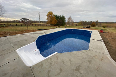 Large elegant backyard concrete and custom-shaped pool photo in Louisville