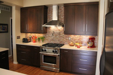 Eat-in kitchen - mid-sized contemporary l-shaped medium tone wood floor eat-in kitchen idea in Denver with dark wood cabinets, solid surface countertops, multicolored backsplash, stainless steel appliances, an island, a double-bowl sink, recessed-panel cabinets and matchstick tile backsplash