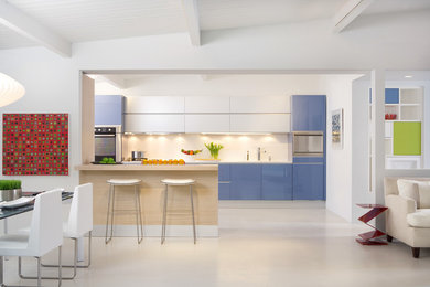 Example of a trendy galley porcelain tile and beige floor open concept kitchen design in Los Angeles with flat-panel cabinets, blue cabinets, a double-bowl sink, quartz countertops, white backsplash, glass tile backsplash, stainless steel appliances, an island and white countertops
